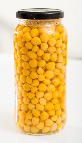 Boiled chickpeas in a glass jar on a white background