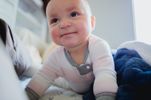 Portraits of a beautiful half Hispanic half Caucasian girl who is happy at home cozy in bed with the blankets. She is 1 year old and smiling for the camera/her daddy the photographer.