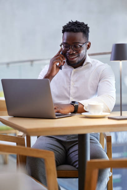 istock An African businessman multitasks while sitting in a cafe. A businessman types on the laptop and talks on the phone with a client. 1415269903