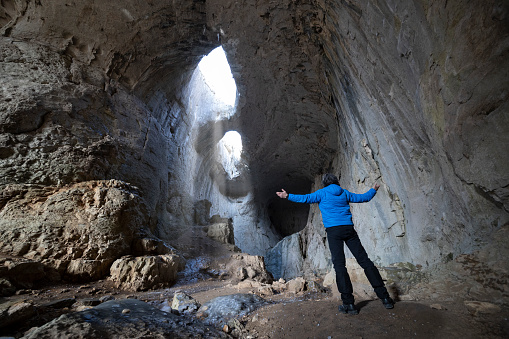 Man traveling and sightseeing beautiful nature phenomena-the Eye of God cave in Bulgaria.