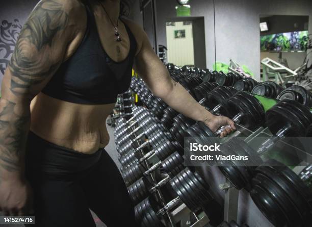 Body Positive Woman Chooses A Dumbbell For Exercise Stock Photo - Download Image Now