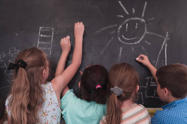 istock Children write and draw on the blackboard in elementary school while learning the basics of education 1415279294