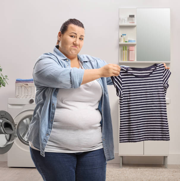 donna che mostra una camicia rimpicciolita in un bagno - shrank foto e immagini stock