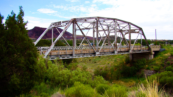 Rustic Metal Truss Bridge Over A Grassy Riverbed
