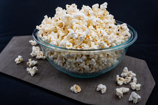 image of popcorn placed in a glass scratch, some below and on a gray stone with a black background
