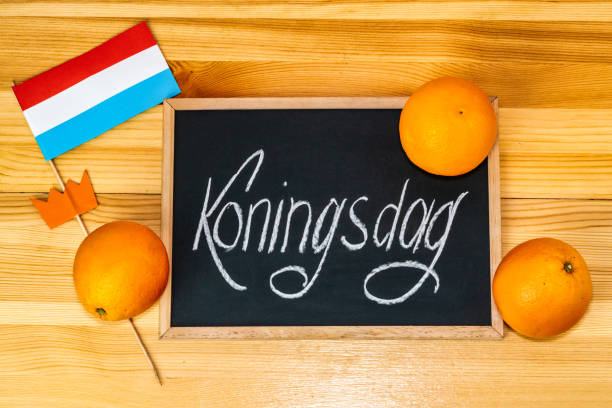Koningsdag or King's Day is a national holiday in the Kingdom of the Netherlands. Painted oranges and the flag of the Netherlands on a chalkboard background stock photo