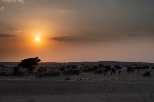 Beautiful sunset at sand dunes of Thar desert, Rajasthan, India. Tourists returing to camps after enjoying the nice view.