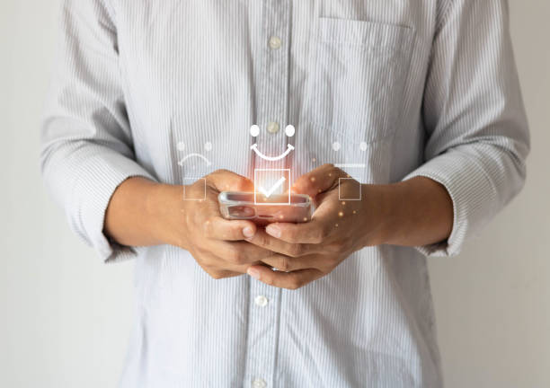 istock Customer service evaluation and satisfaction concept. businessman using a smartphone and pressing face emoticon smile in satisfaction on the virtual touch screen. 1415291146