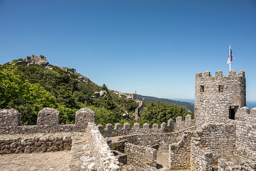 May 26, 2022, Sintra Mountain, Sintra, Lisboa, Portugal: A view of Sintra Mountain with the walls of the Moorish Castle weaving through its trees, on a pleasant, sunny, spring day. The Moorish Castle is a hilltop medieval castle located on Sintra Mountain high above Sintra, Portugal.