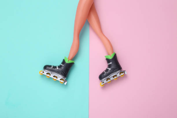 istock Doll legs with roller skates on blue-pink pastel background. Top view. Flat lay 1415300306