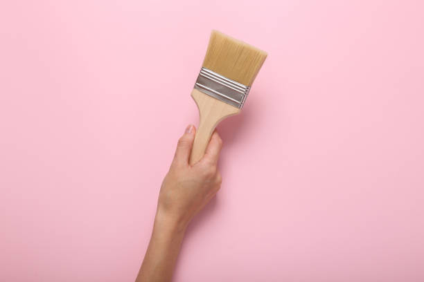 istock Hand holding Paint brush on pink background 1415300345