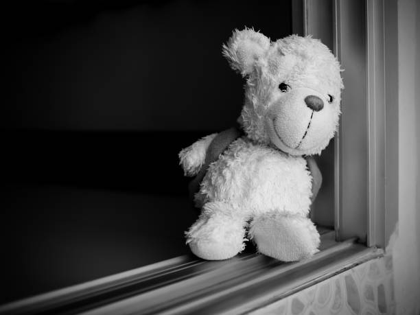 istock Teddy bear siiting on door home.black and white photo. 1415307205