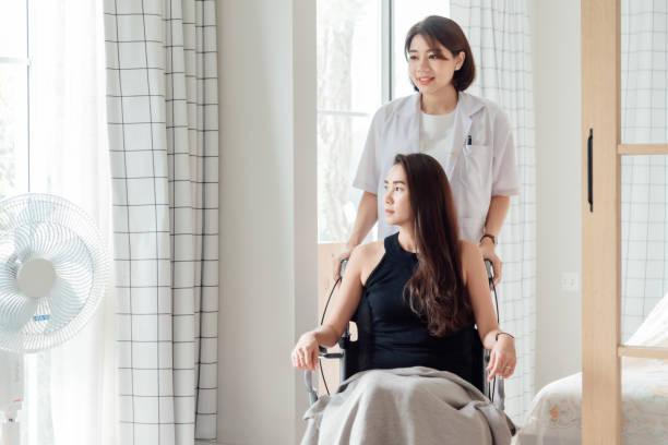 A female doctor or nurse is looking after a patient in a wheelchair. stock photo