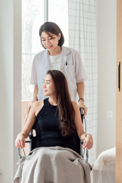 A female doctor or nurse is looking after a patient in a wheelchair. stock photo
