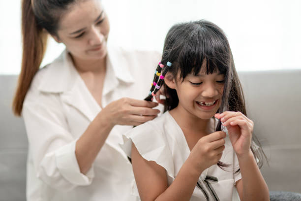 istock Young Asian mother tying daughter's hair 1415308747