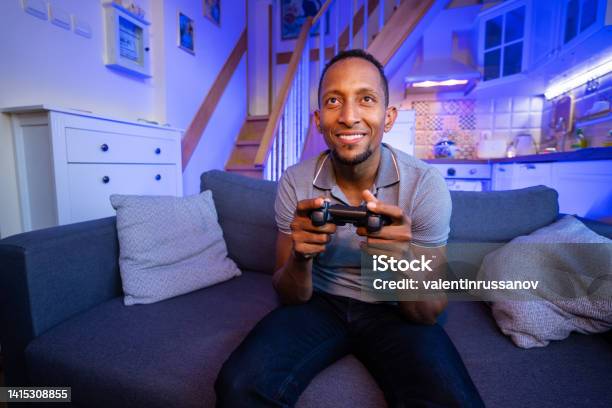 Smiling Brazilian Young Man Enjoying Videogame On Playstation Having Fun At Home Stock Photo - Download Image Now