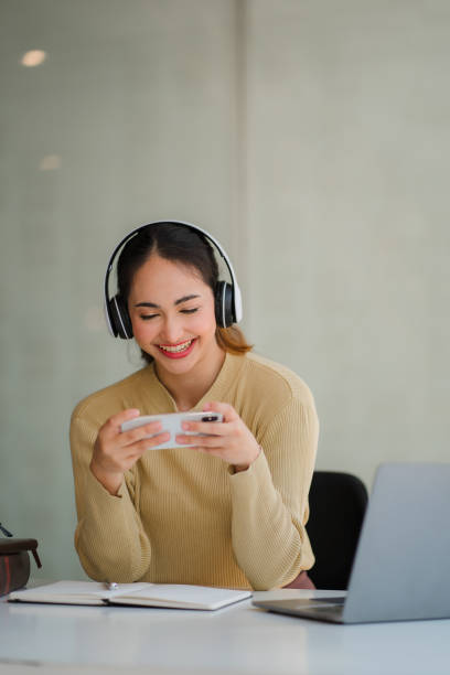istock A young Asian student studying online using headphones and a laptop takes notes in a notebook sitting at her desk at home. 1415308910