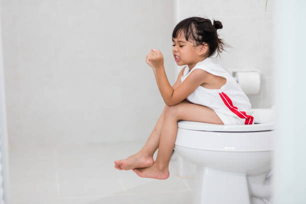 The little girl is sitting on the toilet suffering from constipation or hemorrhoid. The little girl is sitting on the toilet suffering from constipation or hemorrhoid. constipation kids stock pictures, royalty-free photos & images