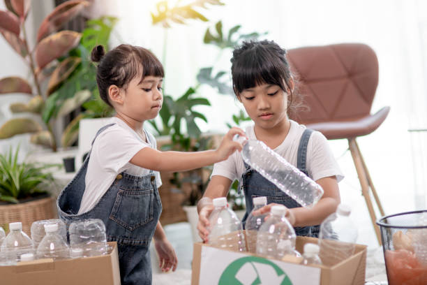 istock Smiling children having fun while segregating plastic bottles and paper into a bin 1415310689