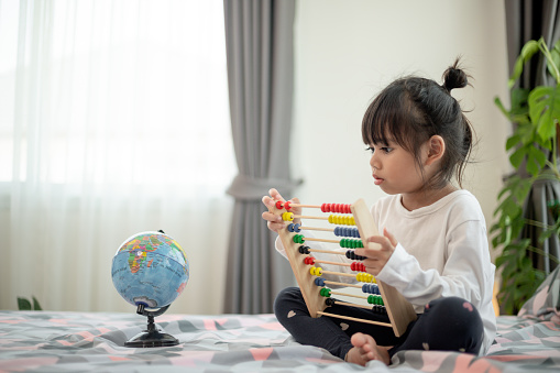 child kid  playing with abacus toy on bed