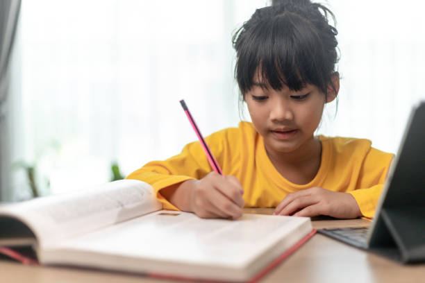 istock Kid holding pencil wring on paper, Child using digital tablet searching information on internet for his homework, Home schooling, E-learning online education 1415310990