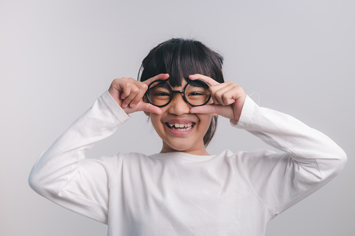 education, school and vision concept - smiling cute little girl in black glasses
