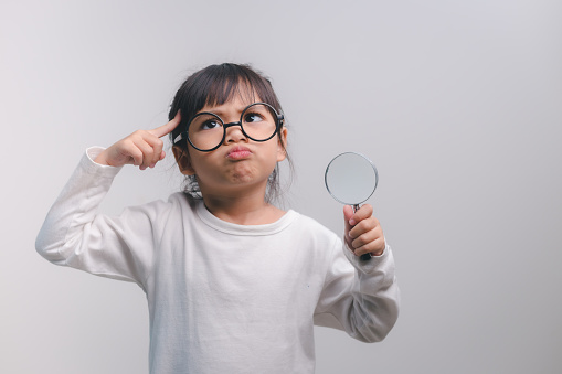 Little girl child holding a magnifying glass on white background