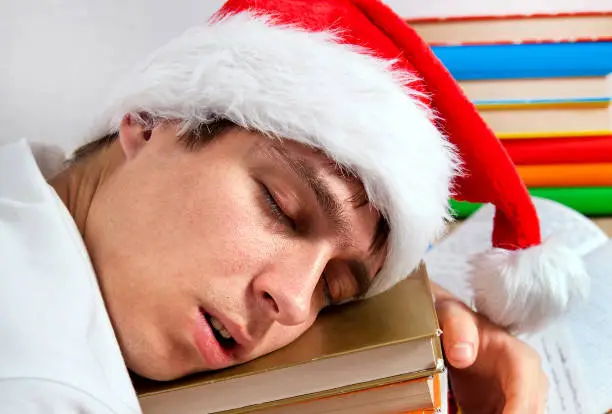 Tired Student in Santa Hat sleep on the Books closeup