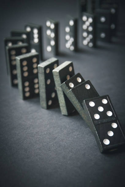istock Black dominoes chain on dark table background 1415312507