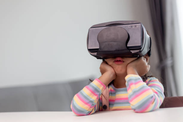 istock Child with virtual reality headset sitting behind table indoors at home 1415312588