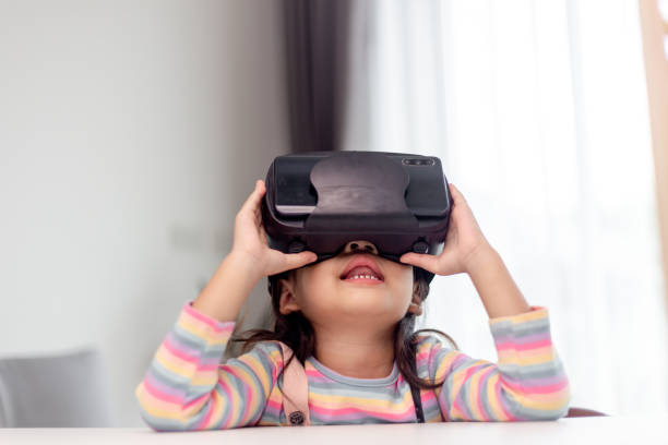 istock Child with virtual reality headset sitting behind table indoors at home 1415312589