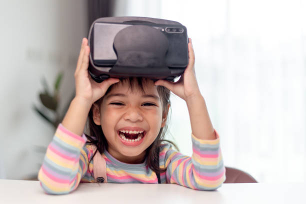 istock Child with virtual reality headset sitting behind table indoors at home 1415312590