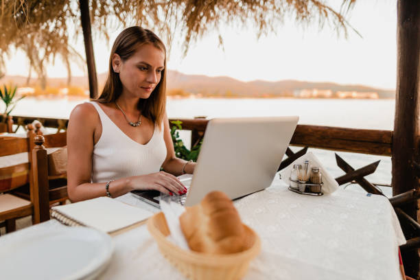 istock Woman using a laptop during her vacation at the seaside 1415313322