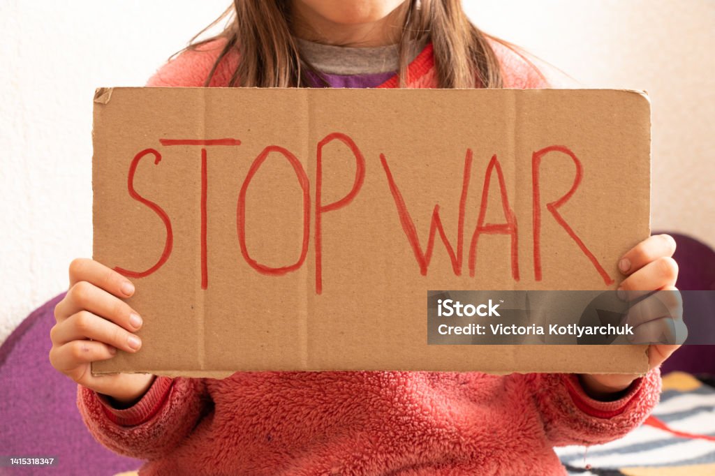 A little girl holds a poster with the words stop the war at her home in Ukraine and asks to stop the war in Ukraine, the children ask, a protest A little girl holds a poster with the words stop the war at her home in Ukraine and asks to stop the war in Ukraine, the children ask, a protest action Aggression Stock Photo