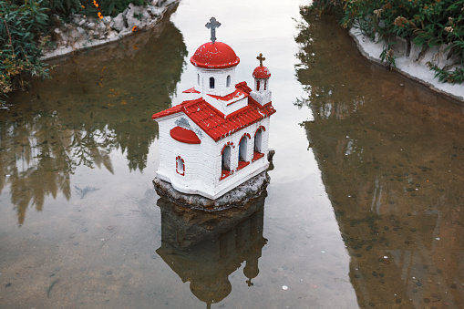 Church on the water . Miniature place of worship . Fountain water with coins