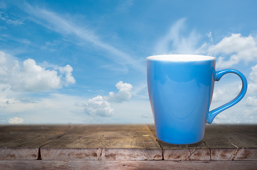 Blue coffee cup on wood table background in the morning