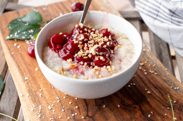 Millet breakfast porridge with cherry compote and roasted nuts stock photo