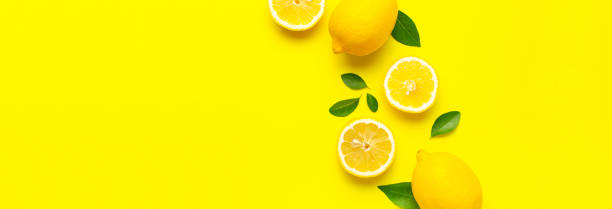 istock Creative background with fresh lemons and green leaves on bright yellow background. Top view flat lay copy space. Lemon fruit citrus minimal concept vitamin C. Composition with whole, slices of lemons 1415326919