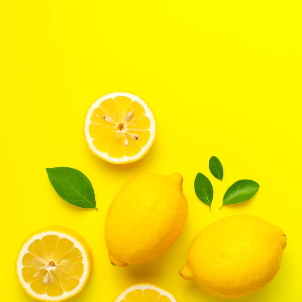 istock Creative background with fresh lemons and green leaves on bright yellow background. Top view flat lay copy space. Lemon fruit citrus minimal concept vitamin C. Composition with whole, slices of lemons 1415326927