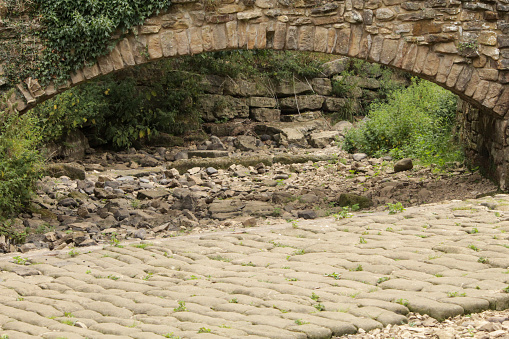 Empty river, dry river bed under stone bridge in drought