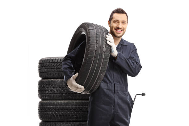 istock Car mechanic with a tire on his shoulder 1415329719