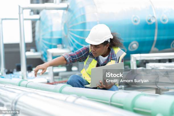 Female Engineer Working With Laptop Computer For Checks Or Maintenance In Sewer Pipes Area At Construction Site African American Woman Engineer Working In Sewer Pipes Area At Rooftop Of Building Stock Photo - Download Image Now