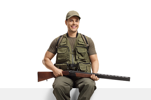 Hunter with a rifle sitting on a blank board isolated on white background
