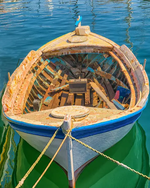An old wooden weathered fishing boat is moored with an old battery left on its deck. Stock Image.