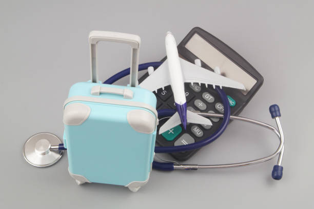 istock Airplane on calculator with stethoscope and suitcase on gray background. 1415332500