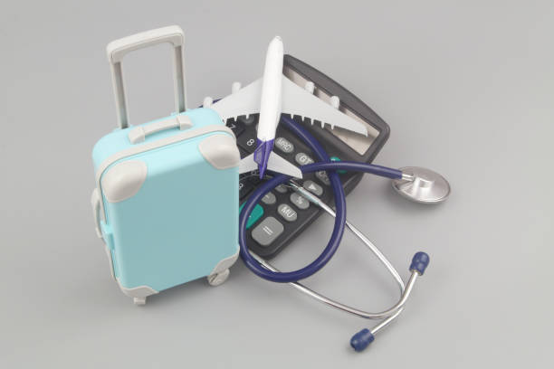 istock Airplane on calculator with stethoscope and suitcase on gray background. 1415332512