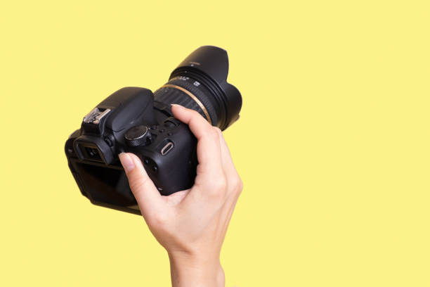 Camera in female hand iolated on yellow background.