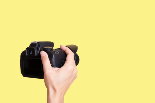 istock Camera in female hands in different positions on a yellow background 1415333991
