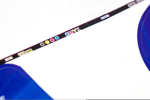 A process field along the edge of the printed material with colorfulness information and ink alignment markers. Close-up of the edge of a printed sheet of paper. CMYK system. Selective focus.