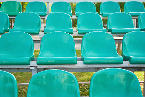 Empty turquoise plastic seats on stands of stadium in open. Concept of sport lifestyle.